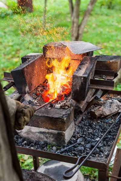 Herrero calienta varilla de hierro en horno de forja —  Fotos de Stock