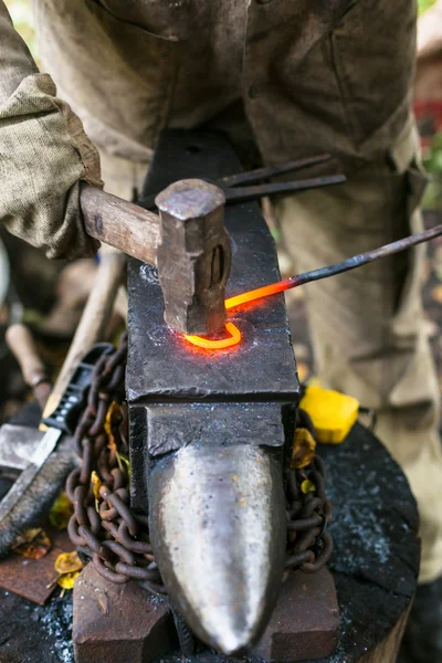 Curvas de ferreiro haste de ferro com martelo em anvi — Fotografia de Stock