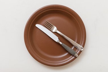 çatal bıçak takımı ile kahverengi plaka üstten görünüm beyaz