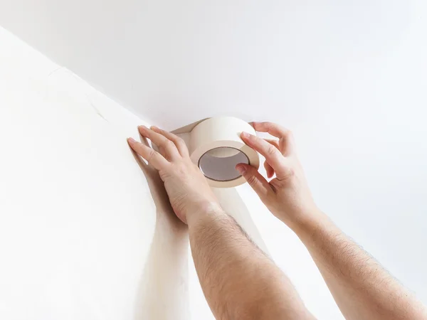 Worker mounts sticky tape on wall before painting — Stock Photo, Image