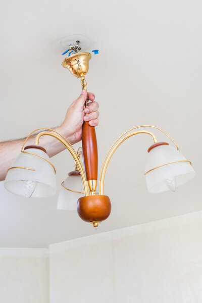 electrician removes hanging ceiling chandelier