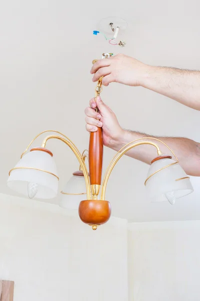 Electrician removes ceiling light for repairing — Stockfoto