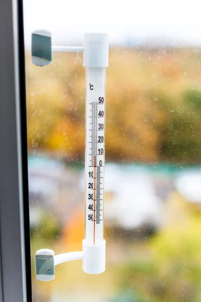 Открытый термометр на стекле домашнего окна осенью — стоковое фото