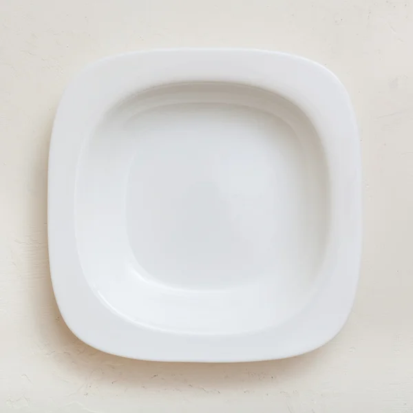 Top view of square white deep plate on plaster — ストック写真