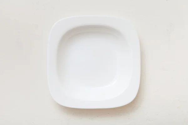 Above view of square white deep plate on plaster — Stock Photo, Image