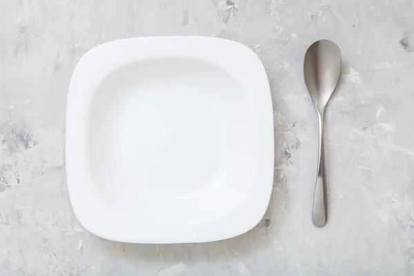 stock image top view square white bowl and spoon on concrete