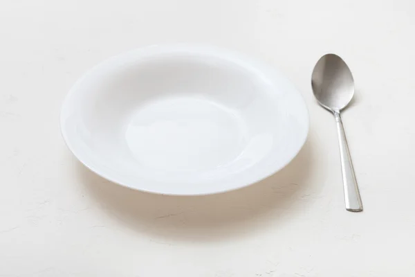 White deep plate and spoon on plaster — Φωτογραφία Αρχείου