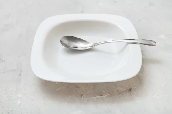 Cuenco blanco cuadrado con cuchara blanca sobre hormigón —  Fotos de Stock