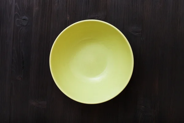 Top view of green bowl on dark brown table — Stock fotografie