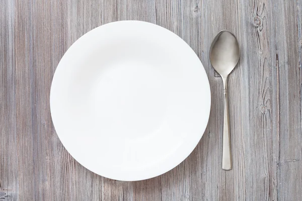 Top view deep plate and spoon on gray brown table — Stock Photo, Image