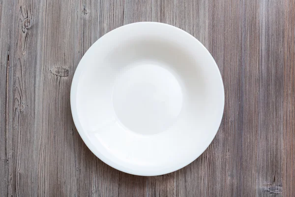 Above view of white deep plate on gray brown table — Stockfoto
