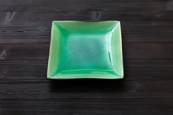 Green square saucer on dark brown table — Stockfoto