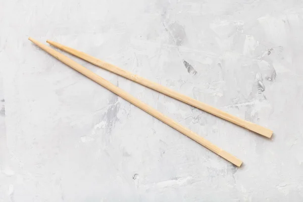 Wooden disposable chopsticks on concrete board — Stock Photo, Image