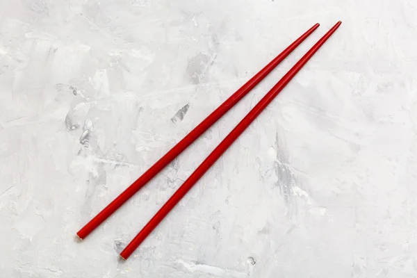 Red wooden chopsticks on concrete board — Stock fotografie