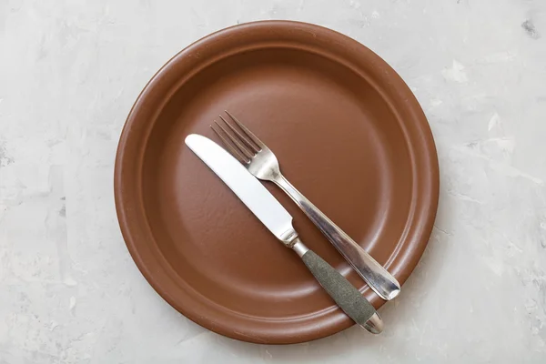 Top view of brown plate with flatware on concrete — Stockfoto