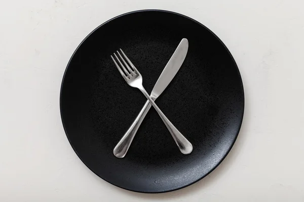 Top view of black plate with cultery on white — Stock Photo, Image