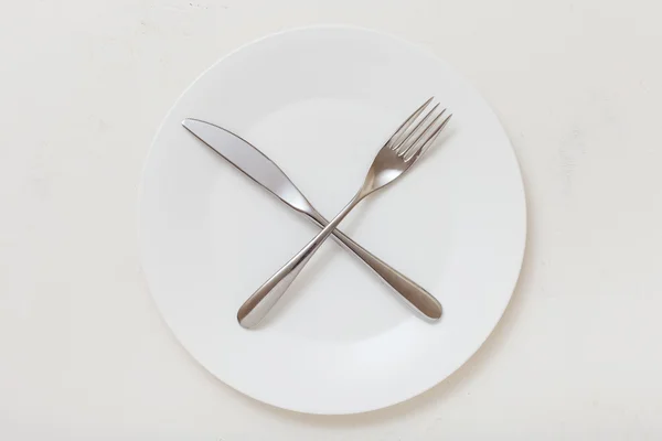 Top view of white plate with cultery on white — Stock fotografie