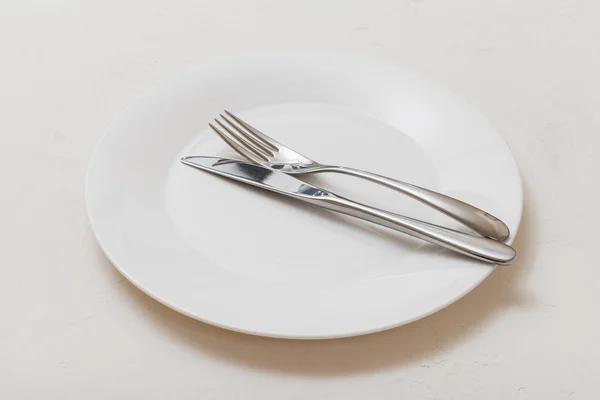 White plate with parallel knife, spoon on white — Stock Photo, Image