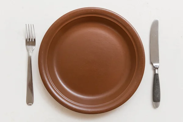 Draufsicht auf braunen Teller mit Messer, Löffel auf weißem — Stockfoto