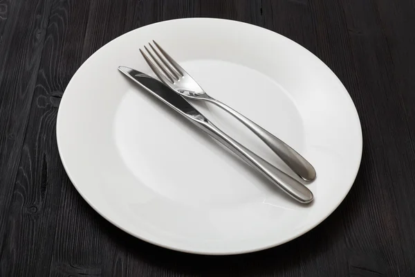 White plate with parallel knife, spoon on dark — Stockfoto