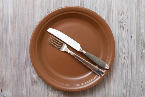 Top view of brown plate with flatware on gray — Stock fotografie