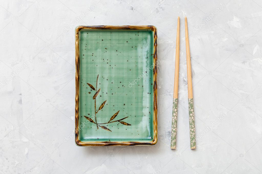 top view of green plate and chopsticks on concrete