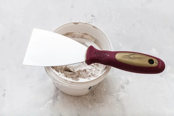 Metal spatula on tube with putty — Stock fotografie