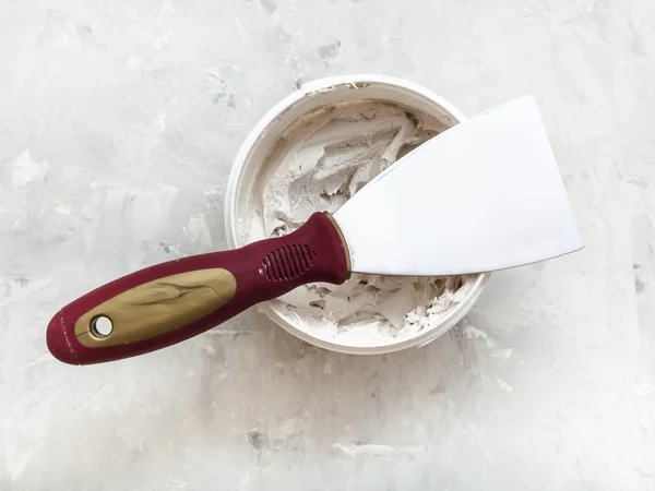 Metal spatula on container with putty — Stockfoto