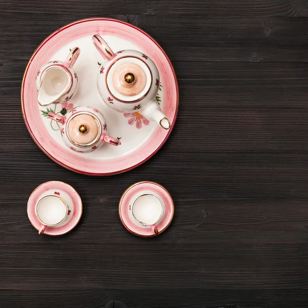 Top view of pink tea set on dark brown board — Stock Photo, Image