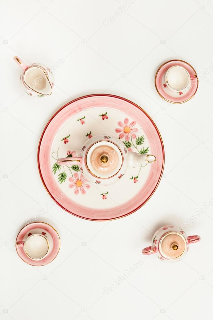 top view of pink porcelain tea set on white paper