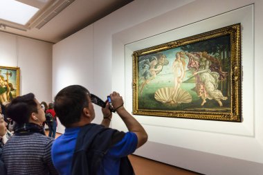 tourist takes photo in room of Uffizi Gallery clipart