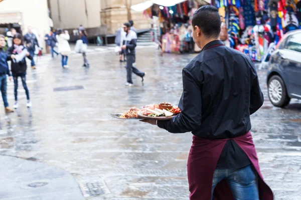 Camarero con platos con comida italiana al aire libre — Foto de Stock