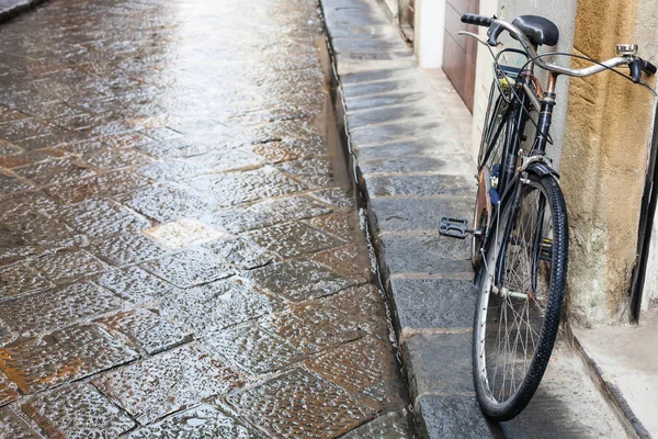 Bicicleta en la calle mojada en Florencia ciudad bajo la lluvia —  Fotos de Stock