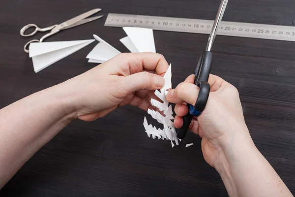Ręka z nożyczkami odciąć śnieżynka z papieru — Zdjęcie stockowe