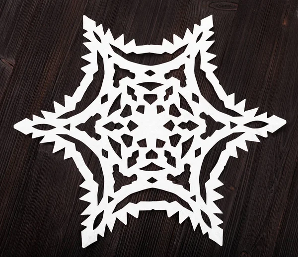Χαρτί snowflake σε σκούρο καφέ τραπέζι από ξύλο — Φωτογραφία Αρχείου