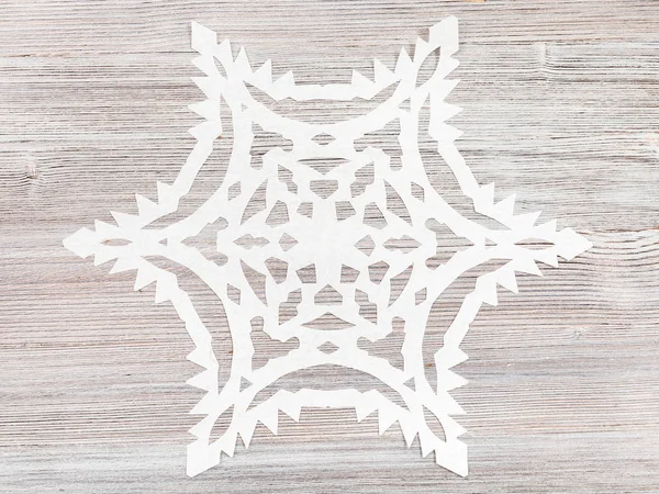 Снежинка вырезанная из бумаги на светло-коричневой поверхности — стоковое фото