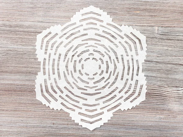 Snowflake cut out of paper on light brown table — Stock Photo, Image