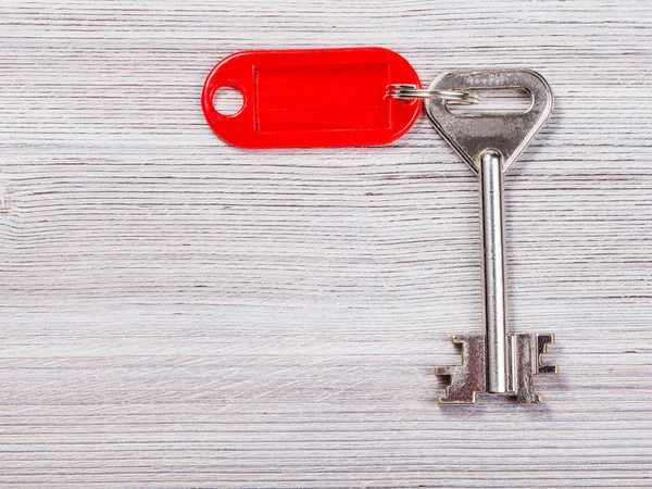 Llave grande de la puerta con el llavero rojo en tablero de madera — Foto de Stock