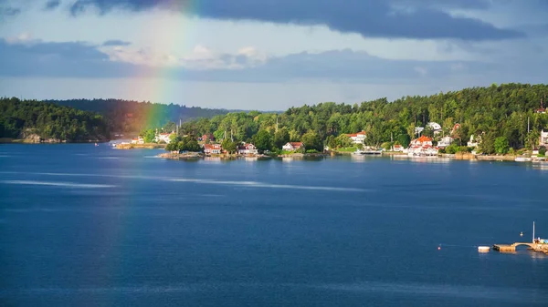 Green shore of Baltic Sea with village and rainbow — Stock Photo, Image