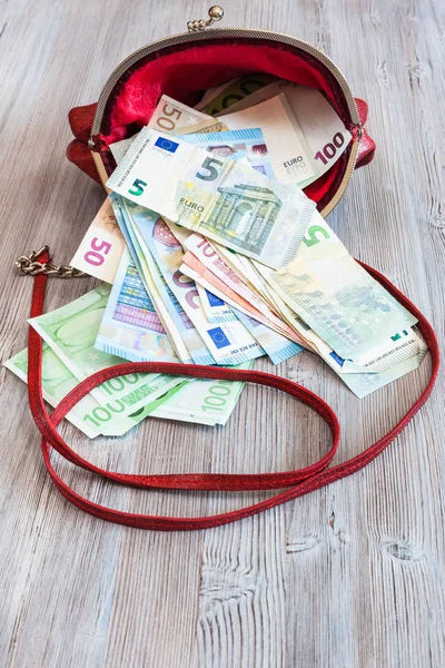 Различные банкноты евро выпадают из красной сумочки — стоковое фото