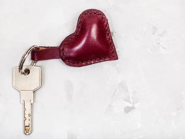 Clé de porte avec porte-clés en forme de coeur sur béton — Photo