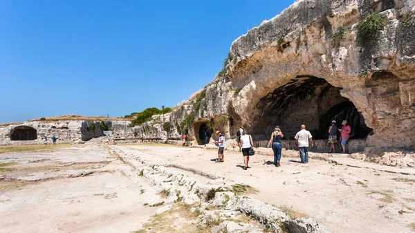 Turistas cerca de cuevas artificiales en la ciudad de Siracusa — Foto de Stock