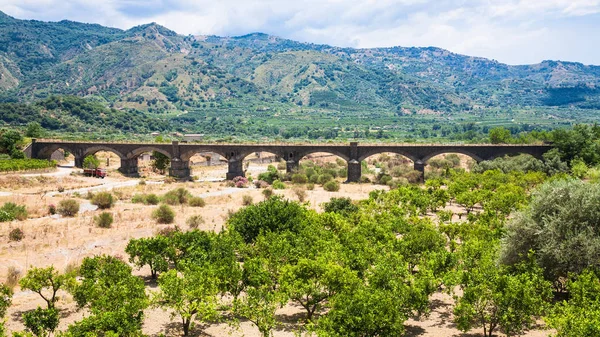 Jardín de cítricos y puente en el valle del río Alcántara — Foto de Stock