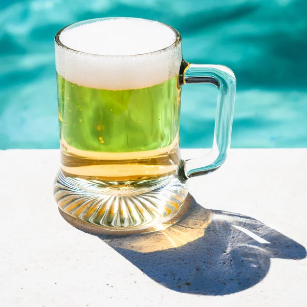 Kubek zimnego piwa na basenie — Zdjęcie stockowe