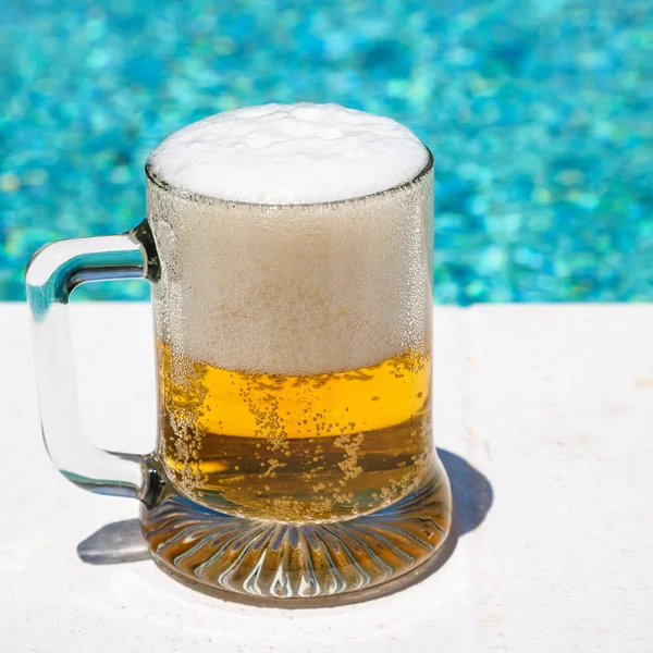 Стекло с холодным светлым пивом на открытом бассейне — стоковое фото
