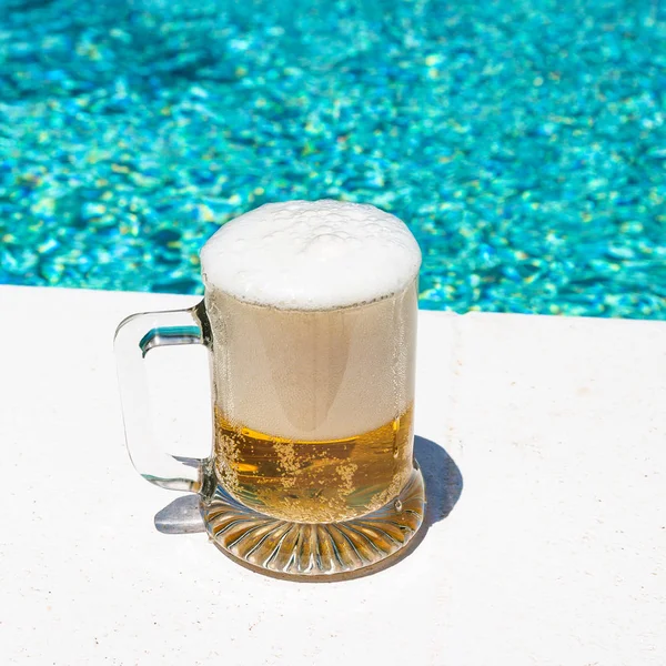 Tasse avec bière froide et légère sur la piscine extérieure — Photo