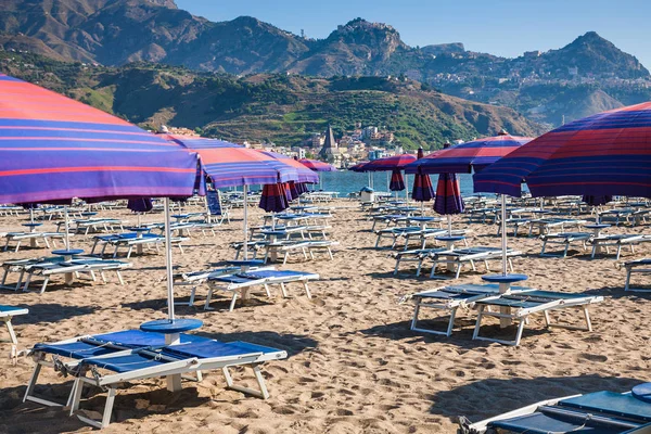 Parassóis e camas na praia urbana em giardini naxos — Fotografia de Stock