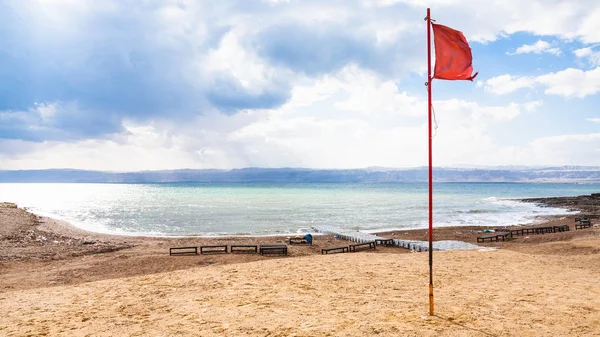 Rode vlag op strand in koude dag op dode zee — Stockfoto