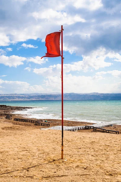 Ed flag on beach of Dead Sea in sunny winter day — Stock Photo, Image