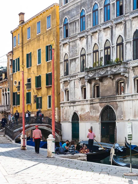 Gondoliers and tourists on waterfront in Venice — Stock Photo, Image